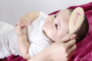 Image of baby enjoying her hair being brushed with a BerryBest baby hair brush, from BerryBest's product range.